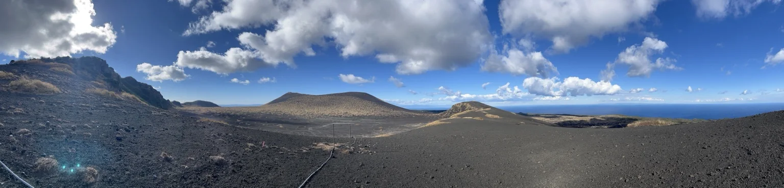 黒い火山地形が広がる裏砂漠のパノラマ